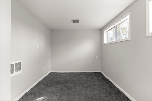 empty room with visible vents, baseboards, and dark carpet