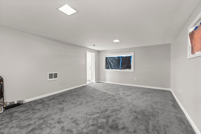 spare room with visible vents, baseboards, and dark carpet