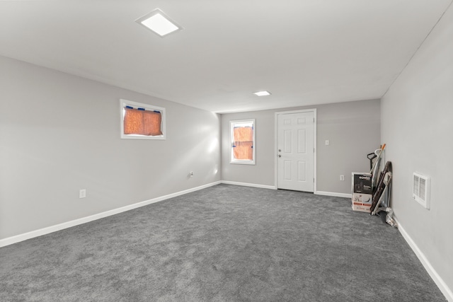 below grade area with baseboards, dark colored carpet, and visible vents