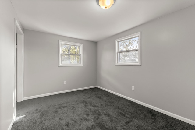 empty room with baseboards and dark colored carpet