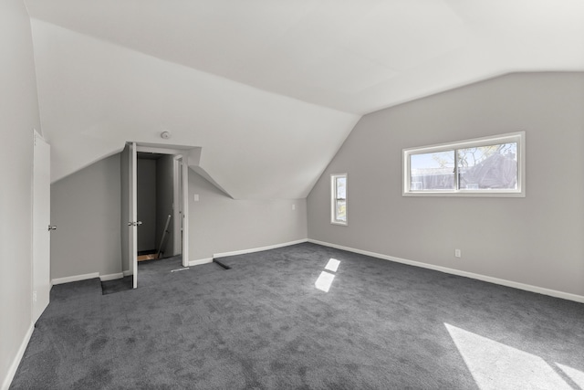 bonus room featuring baseboards, dark carpet, and vaulted ceiling
