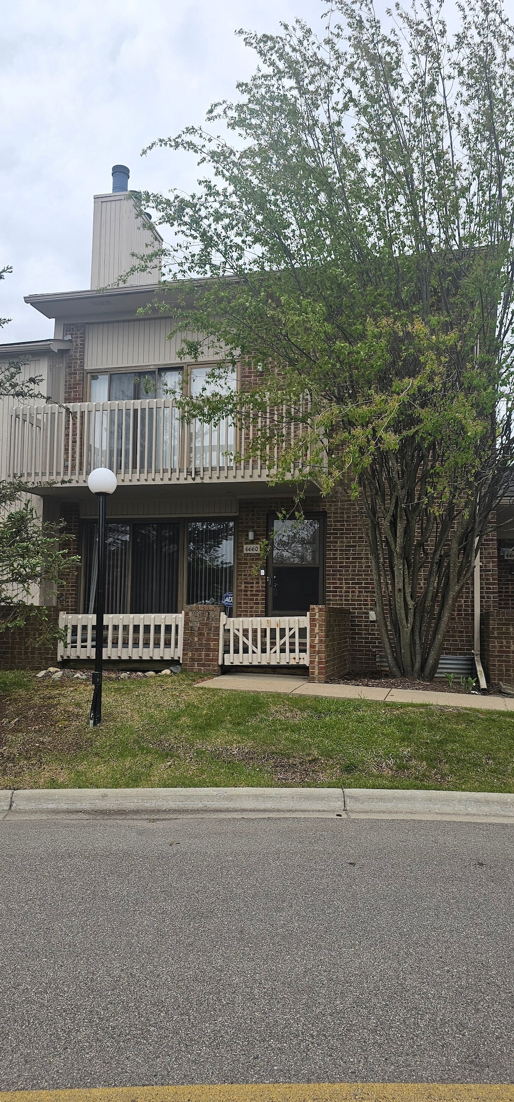 view of front of property with a fenced front yard, a balcony, and brick siding