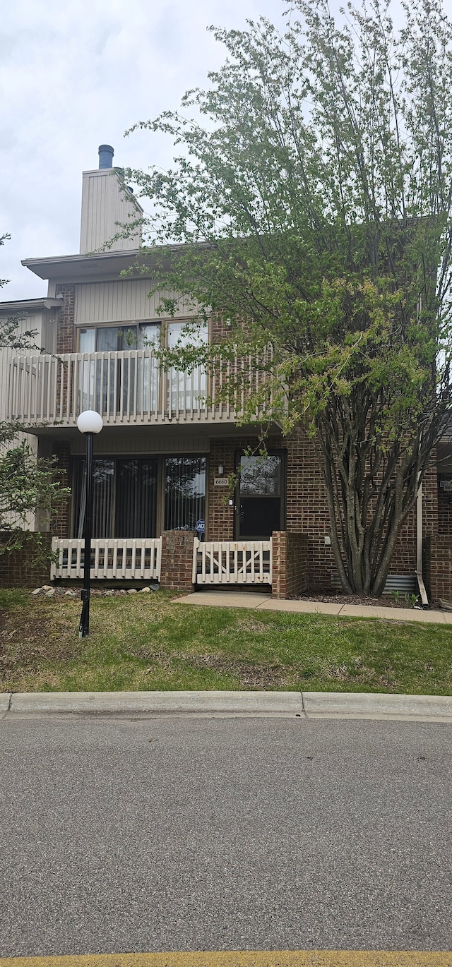 view of front of property with a fenced front yard, a balcony, and brick siding