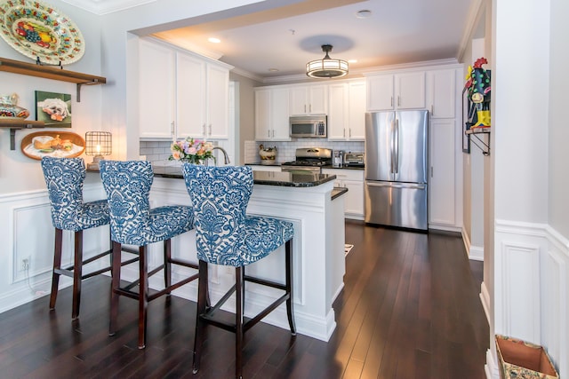 438 Filmore St, Canton, MI 48188 - kitchen with a peninsula, a kitchen bar, white cabinets, wainscoting, and appliances with stainless steel finishes