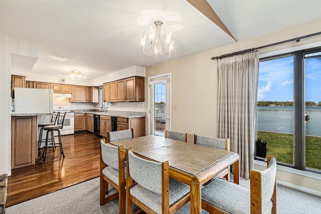 8570 Riverside Dr, Brighton, MI 48116 - dining space featuring a chandelier, a water view, baseboards, and dark carpet