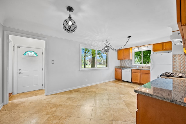 kitchen with backsplash, brown cabinetry, baseboards, and white appliances