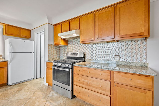 kitchen with freestanding refrigerator, under cabinet range hood, tasteful backsplash, and stainless steel range with gas cooktop