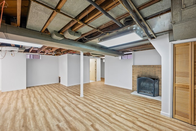 basement featuring baseboards, wood finished floors, and a fireplace
