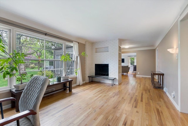 living room with a fireplace, baseboards, and light wood-type flooring