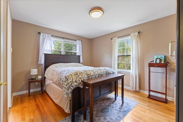 bedroom featuring multiple windows, light wood-type flooring, and baseboards