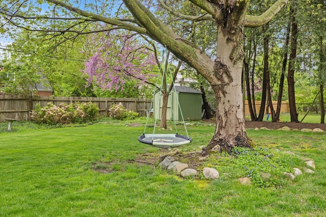 view of yard with a fenced backyard, a shed, and an outbuilding
