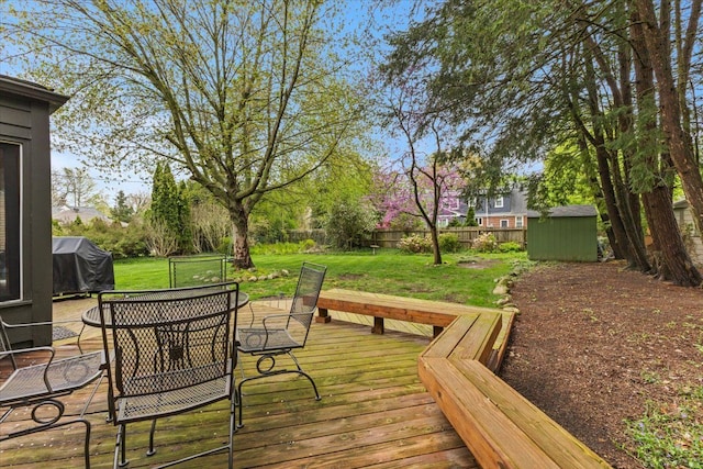 deck featuring a yard, an outdoor structure, a fenced backyard, and a shed