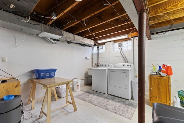laundry area featuring washing machine and clothes dryer, laundry area, concrete block wall, and tile patterned floors