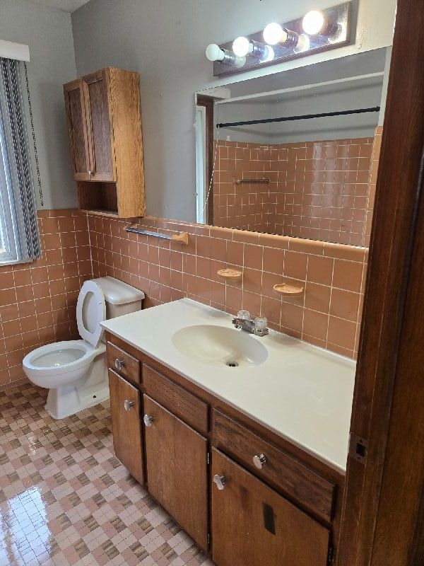 19000 Rosetta Ave, Eastpointe, MI 48021 - bathroom with tile walls, vanity, toilet, a wainscoted wall, and tile patterned floors