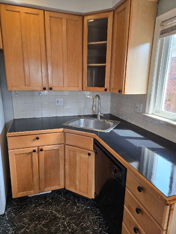 19000 Rosetta Ave, Eastpointe, MI 48021 - kitchen featuring dishwasher, a sink, dark marble finish floors, dark countertops, and tasteful backsplash