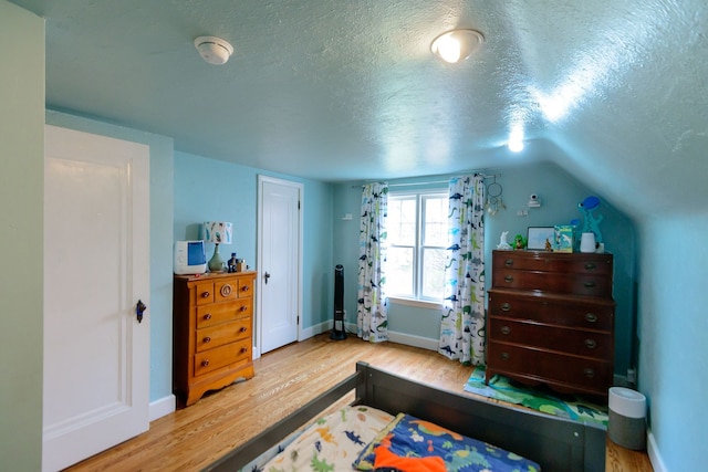 2847 N Custer Rd, Monroe, MI 48162 - bedroom with wood finished floors, a textured ceiling, baseboards, and vaulted ceiling
