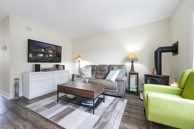 living room with a wood stove, dark wood-style flooring, and baseboards