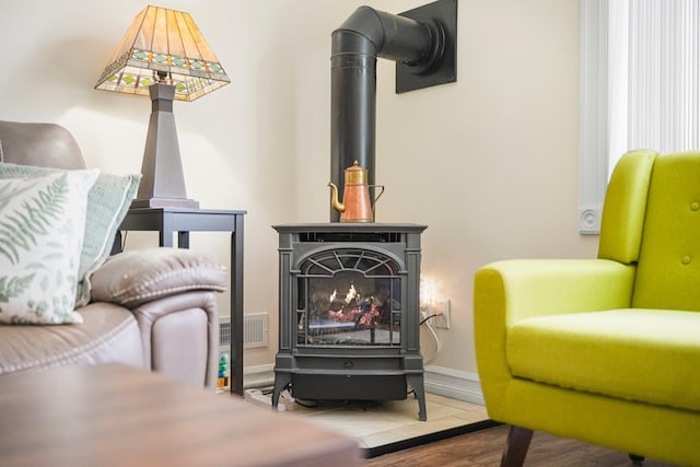 sitting room featuring a wood stove and baseboards