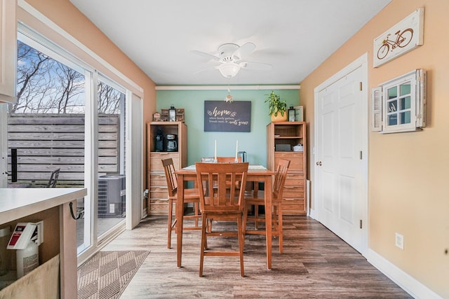 dining room featuring wood finished floors, ceiling fan, and baseboards
