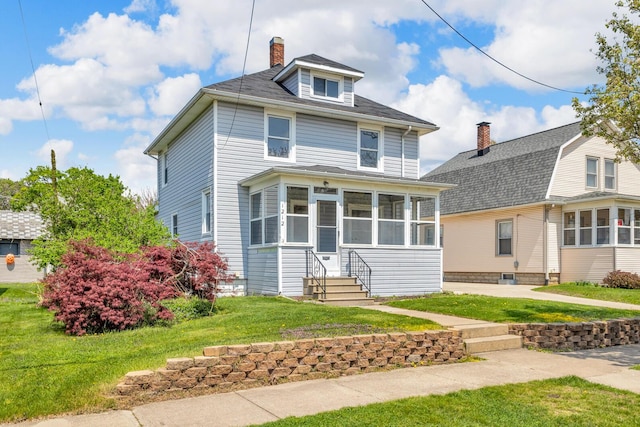 1212 Forest Ave, Jackson, MI 49201 - american foursquare style home featuring a chimney, entry steps, a sunroom, and a front yard