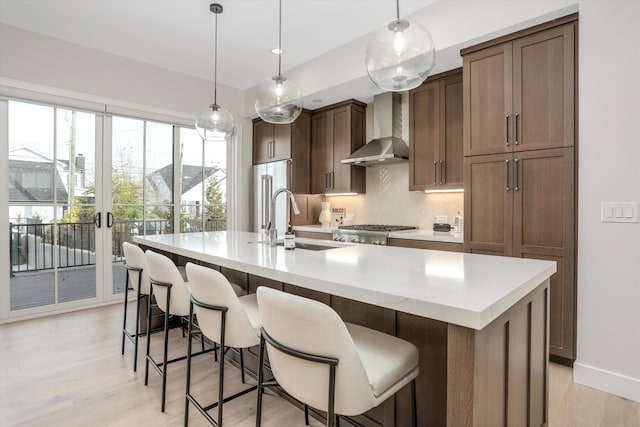 628 Maple St, Plymouth, MI 48170 - kitchen with a sink, backsplash, wall chimney range hood, a center island with sink, and light countertops
