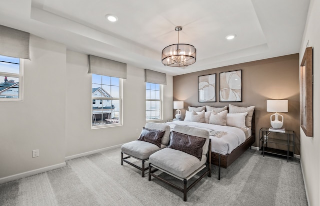 bedroom with a raised ceiling, an inviting chandelier, multiple windows, and carpet floors
