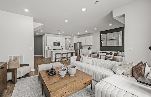 living area with baseboards, visible vents, recessed lighting, and wood finished floors