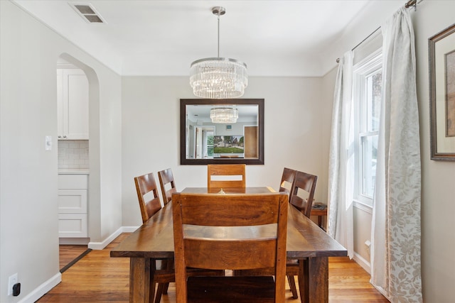 11389 Gold Arbor Rd, Plymouth, MI 48170 - dining area with light wood finished floors, a chandelier, arched walkways, and baseboards