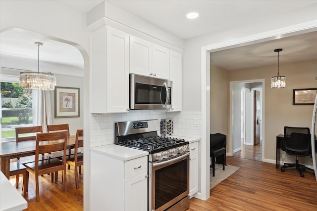 11389 Gold Arbor Rd, Plymouth, MI 48170 - kitchen with stainless steel appliances, a chandelier, backsplash, light countertops, and light wood finished floors