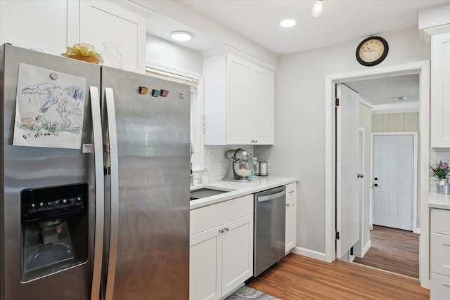 11389 Gold Arbor Rd, Plymouth, MI 48170 - kitchen with appliances with stainless steel finishes, decorative backsplash, wood finished floors, white cabinets, and light countertops