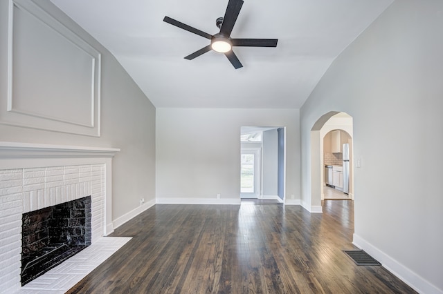 unfurnished living room featuring a ceiling fan, dark wood-style floors, arched walkways, lofted ceiling, and baseboards