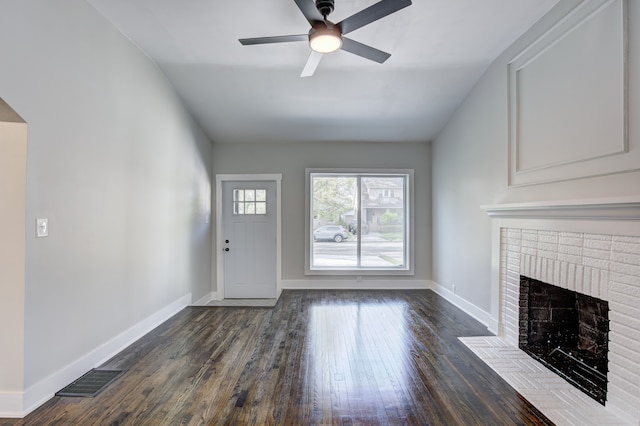 unfurnished living room with a fireplace, dark wood-type flooring, ceiling fan, baseboards, and vaulted ceiling