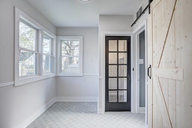 doorway with a barn door, carpet flooring, and baseboards