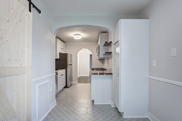 kitchen with light flooring, decorative backsplash, appliances with stainless steel finishes, dark countertops, and white cabinetry