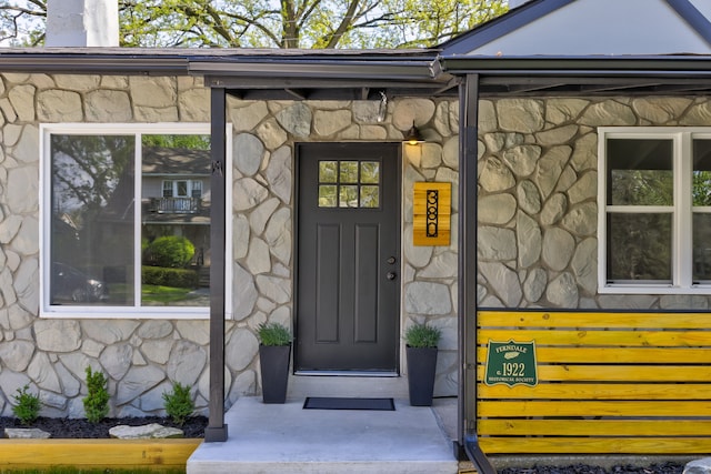 property entrance featuring stone siding and a chimney