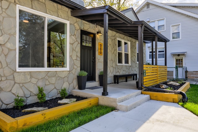 doorway to property featuring stone siding and covered porch