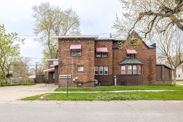 view of front of home with brick siding, concrete driveway, and a front lawn