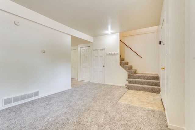 unfurnished living room with carpet, stairs, and baseboards
