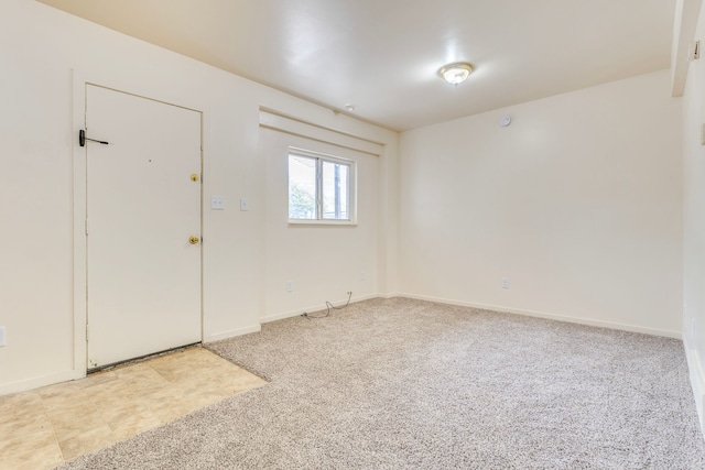 empty room featuring light carpet and baseboards