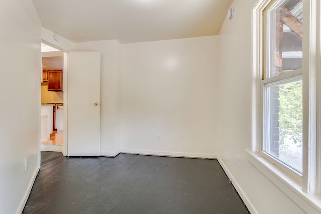 empty room featuring baseboards, dark wood finished floors, and a smoke detector