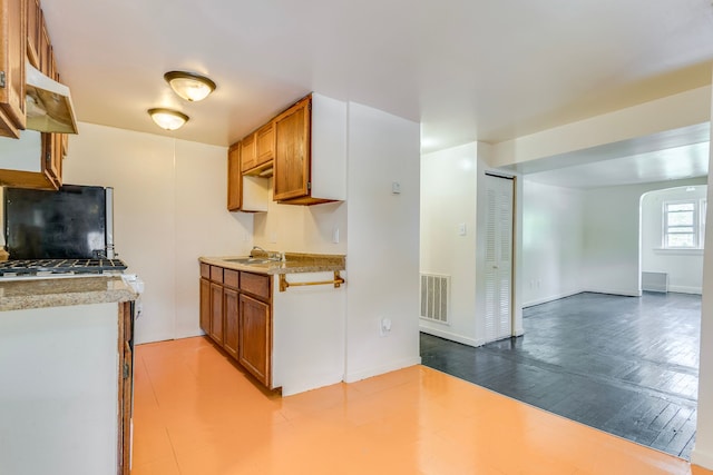 kitchen featuring refrigerator, a sink, brown cabinets, and light countertops