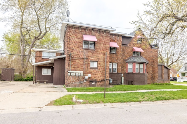 view of front facade featuring brick siding, a front lawn, and concrete driveway