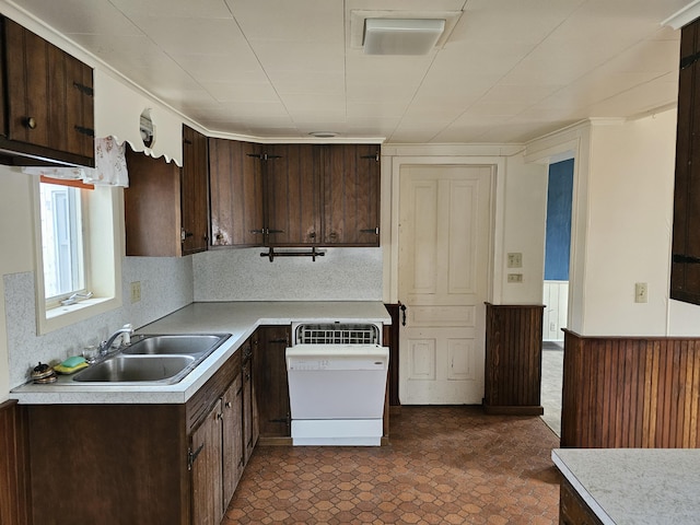 kitchen featuring a sink, light countertops, white dishwasher, wainscoting, and dark brown cabinets