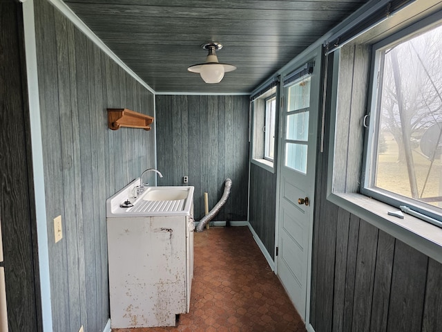 clothes washing area featuring a sink, wood walls, and brick patterned floor