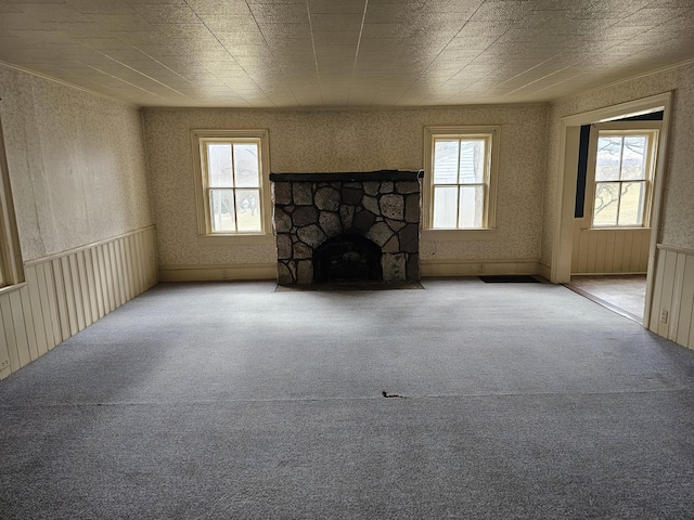 unfurnished living room with a fireplace, carpet, a healthy amount of sunlight, and wallpapered walls