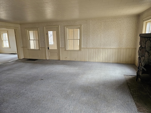 foyer entrance featuring a wealth of natural light, carpet flooring, wallpapered walls, and a wainscoted wall