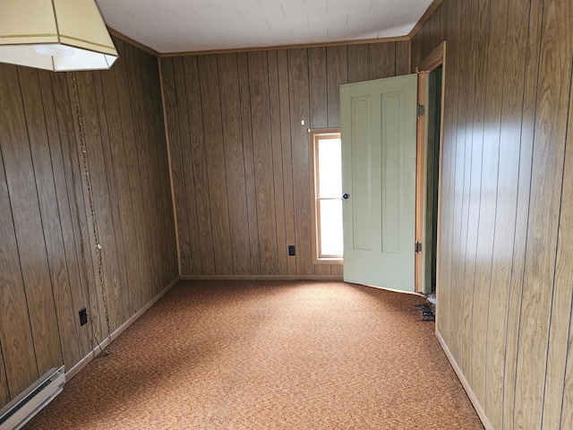 empty room with baseboards, carpet flooring, baseboard heating, and wood walls