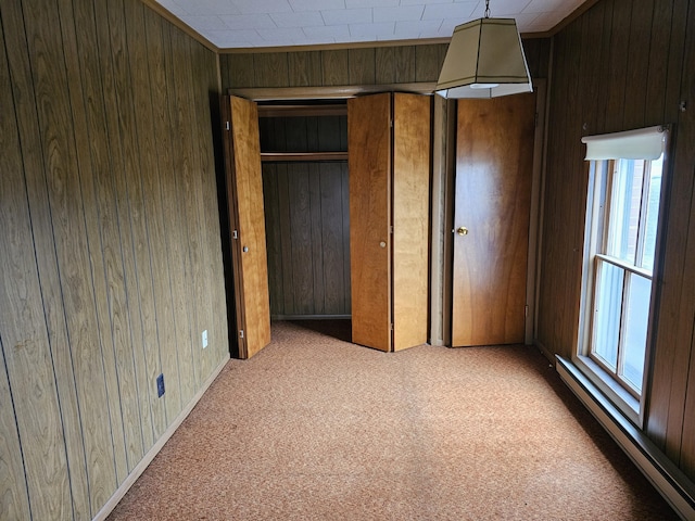 unfurnished bedroom featuring carpet flooring, wooden walls, and a baseboard radiator