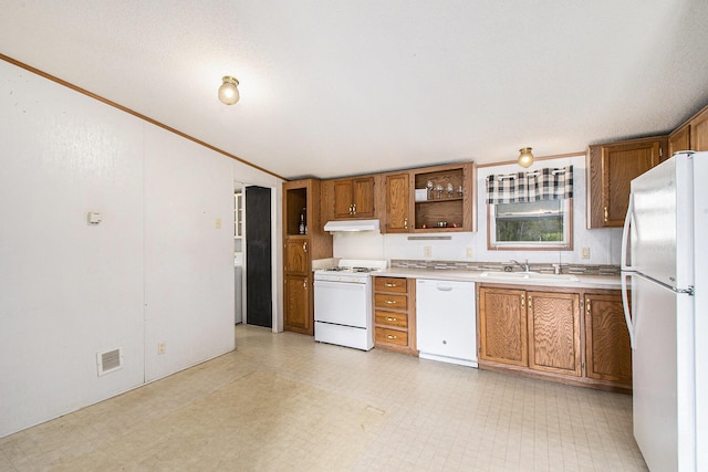 kitchen with a sink, brown cabinetry, white appliances, and light countertops