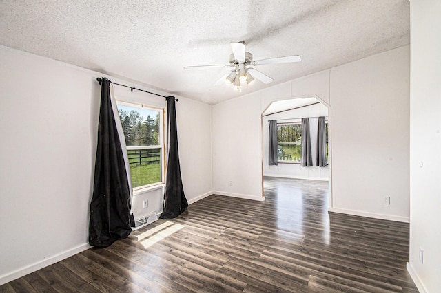 empty room featuring dark wood finished floors, a wealth of natural light, a ceiling fan, and a textured ceiling